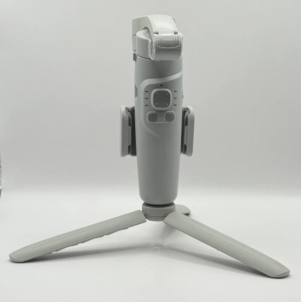 Front view of grey Merak One smartphone gimbal showcasing joystick, mode button, power button, and tripod legs