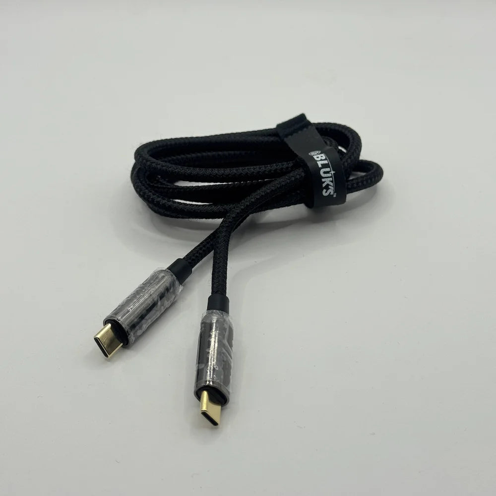 Coiled black BLUK'S BX471 metal cable with cable tie strap on plain background