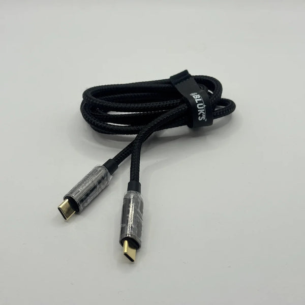 Coiled black BLUK'S BX471 metal cable with cable tie strap on plain background