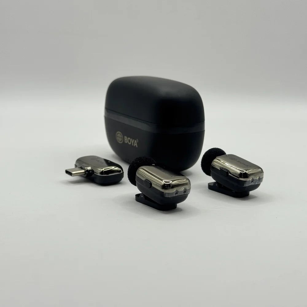 Two chrome-accented BOYA BY-MW10 clip-on wireless transmitter mics and 2-in-1 receiver adapter placed in front of charging case