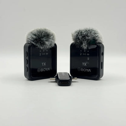 Frontal view of twin BY-V20 wireless transmitter units with furry windscreens and dual plug receiver adapter