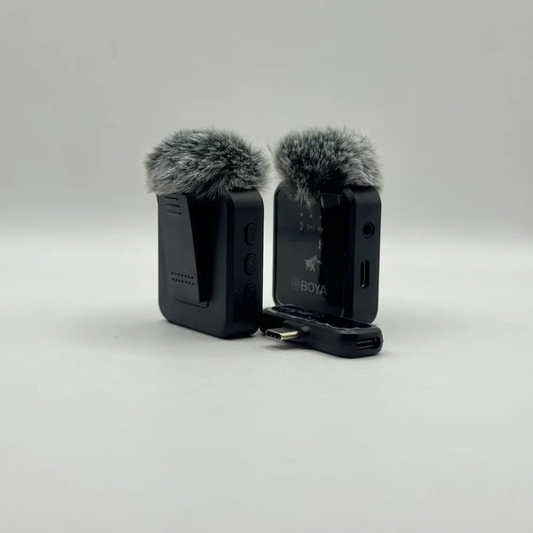 Rear view of black BY-V20 wireless lavalier microphones showing clothing clip attachments and furry wind mufflers